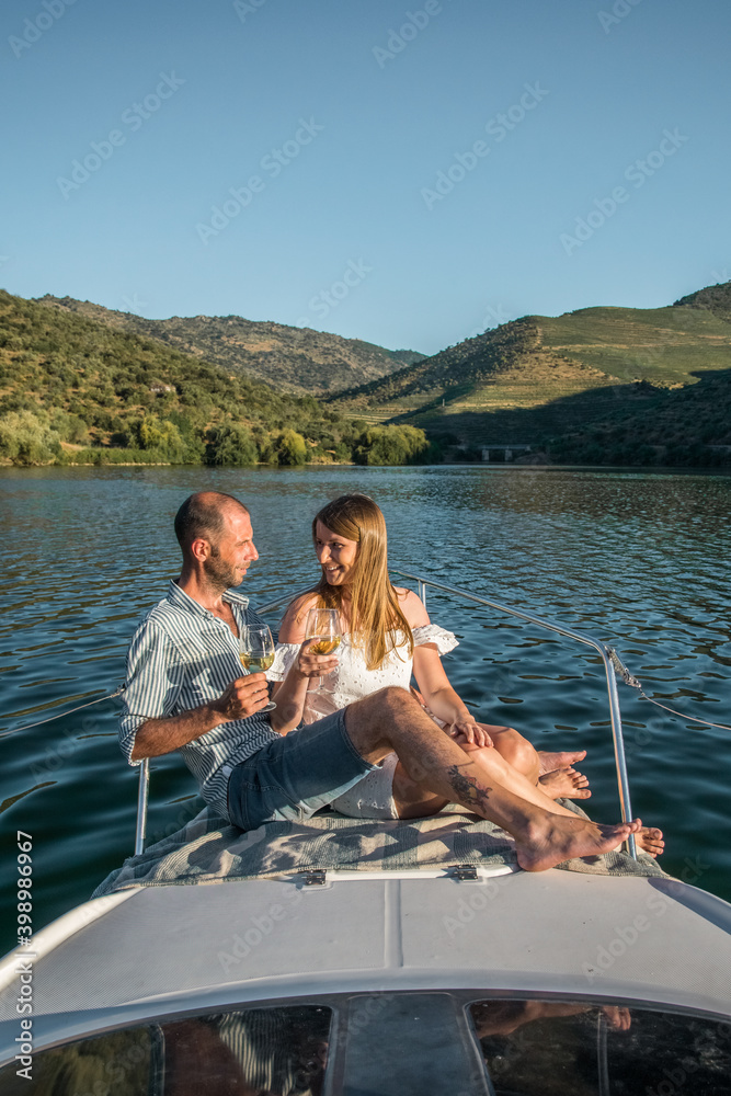 Fototapeta premium Young couple on a yacht holding two glasses of wine