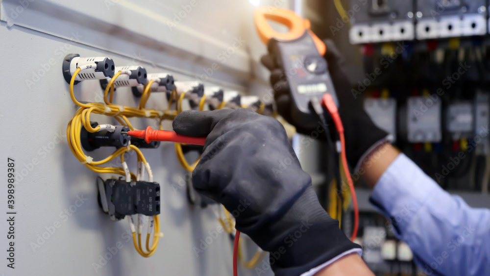 Close-up hand of electrical engineer using measuring equipment to checking electric current voltage at circuit breaker and cable wiring system for maintenance in main power distribution board. Close-up hand of electrical engineer using measuring equipment to checking electric current voltage at circuit breaker and cable wiring system for maintenance in main power distribution board.