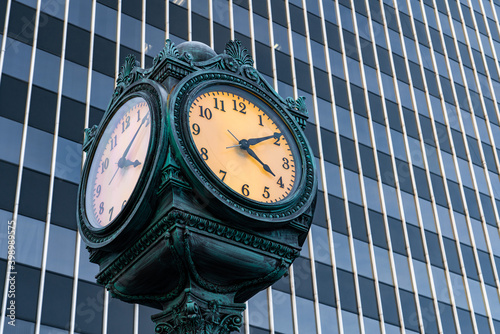 Image of a clock in a city with a business building in the background.