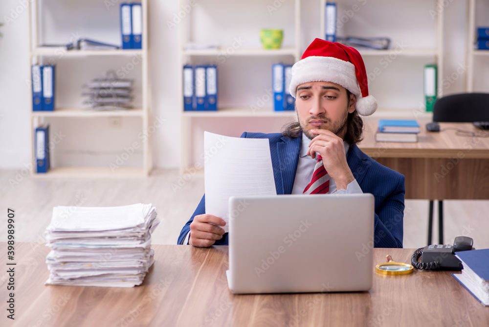 Young male employee working in the office at Christmas Eve Young male employee working in the office at Christmas Eve