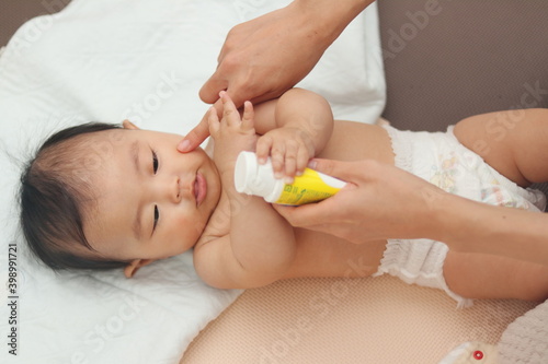 お風呂上りの赤ちゃんに保湿クリームを塗る