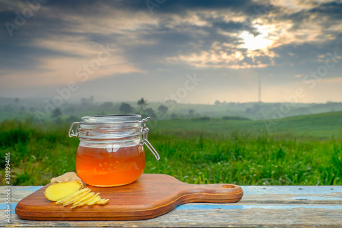 Alternative Medicine with garlic and honey on wooden table. Beautiful sunrise as background.