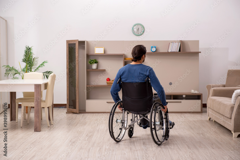 Young man in wheel-chair suffering at home Young man in wheel-chair suffering at home
