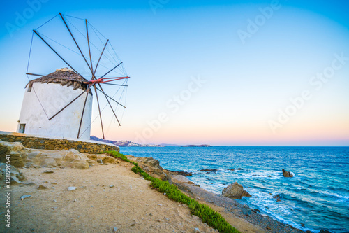 Traditional white windmill near the sea coast at sunrise