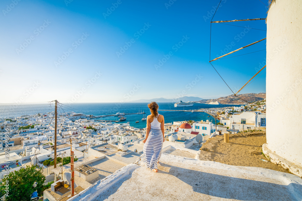 Female tourist looking at Mykonos island in Greece - obrazy, fototapety, plakaty 