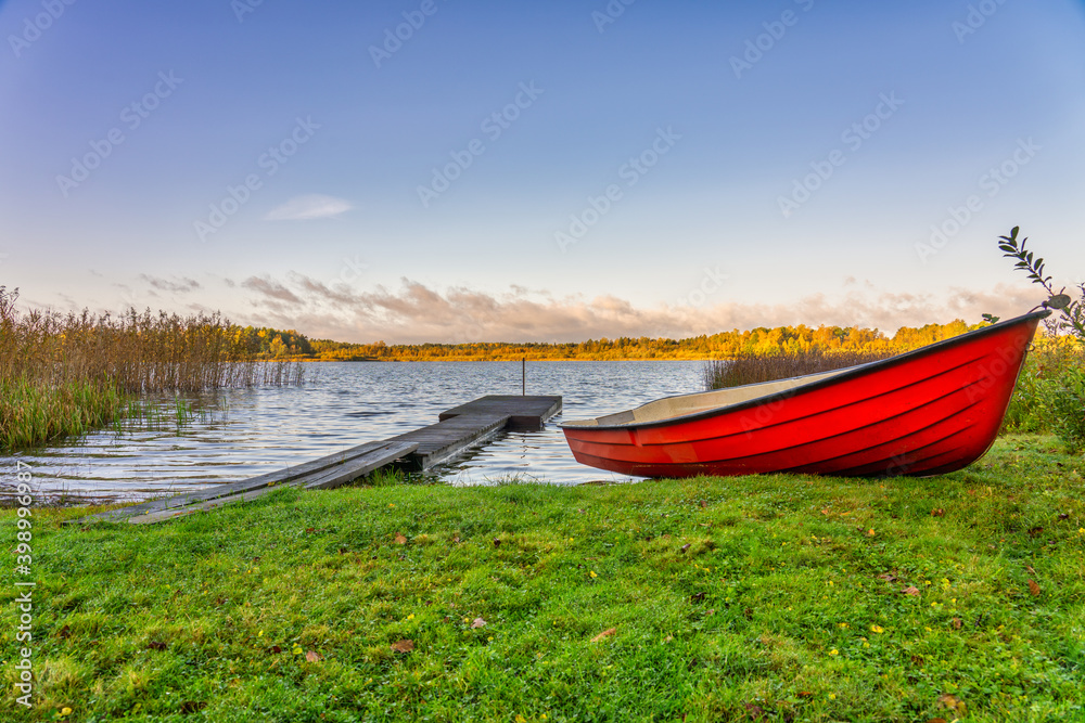 Red boat near empty pier at the lake. Autumn landscape of Sweden