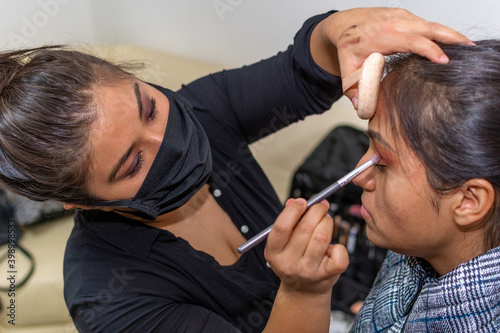 woman dressed in black blouse putting makeup on another younger woman