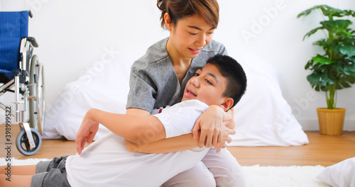 Disabled son has therapy by doing exercise with mother support and care.