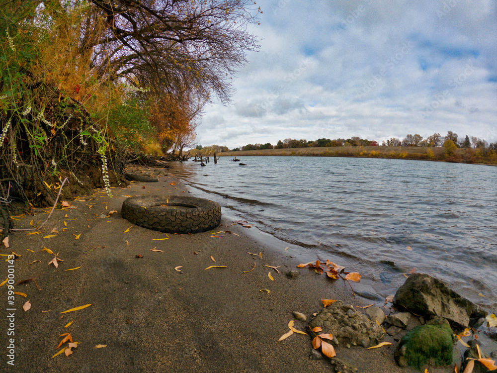 Old tire on the shore of a river in fall 