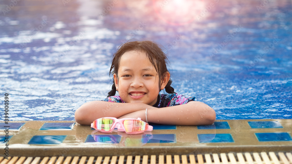 Smiling asian little girl with sunglasses in the pool