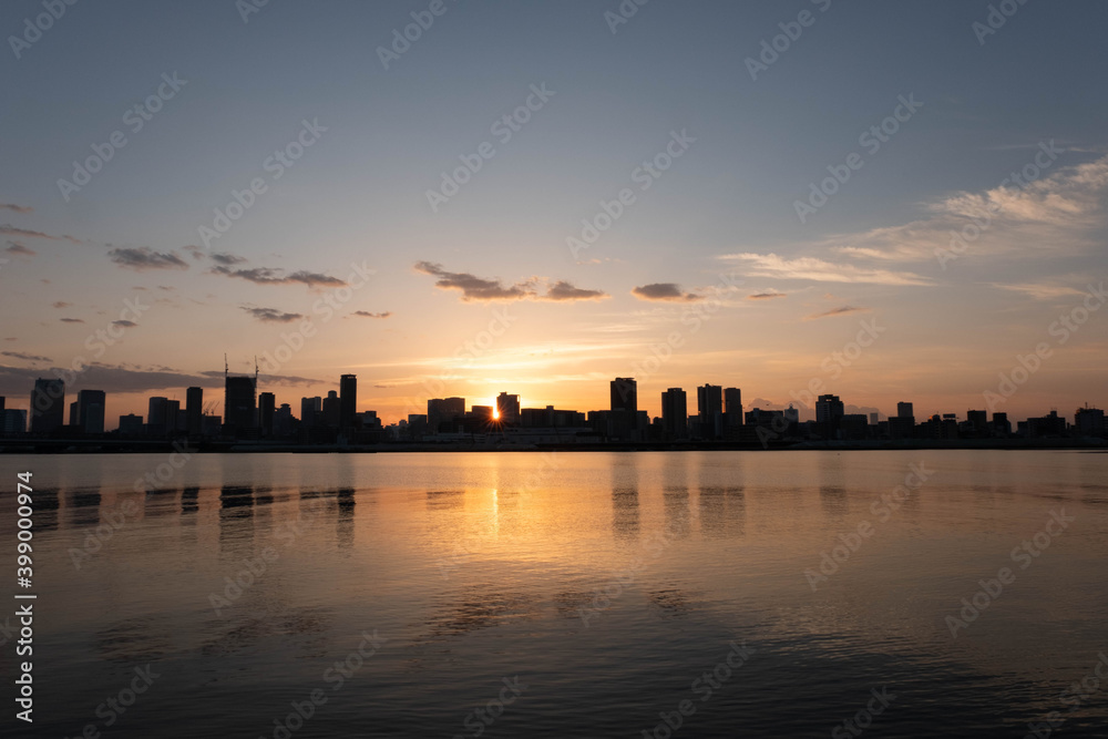 夜明け前、大阪淀川の河川敷から梅田方面。川の水面にビルのシルエットが映り込む