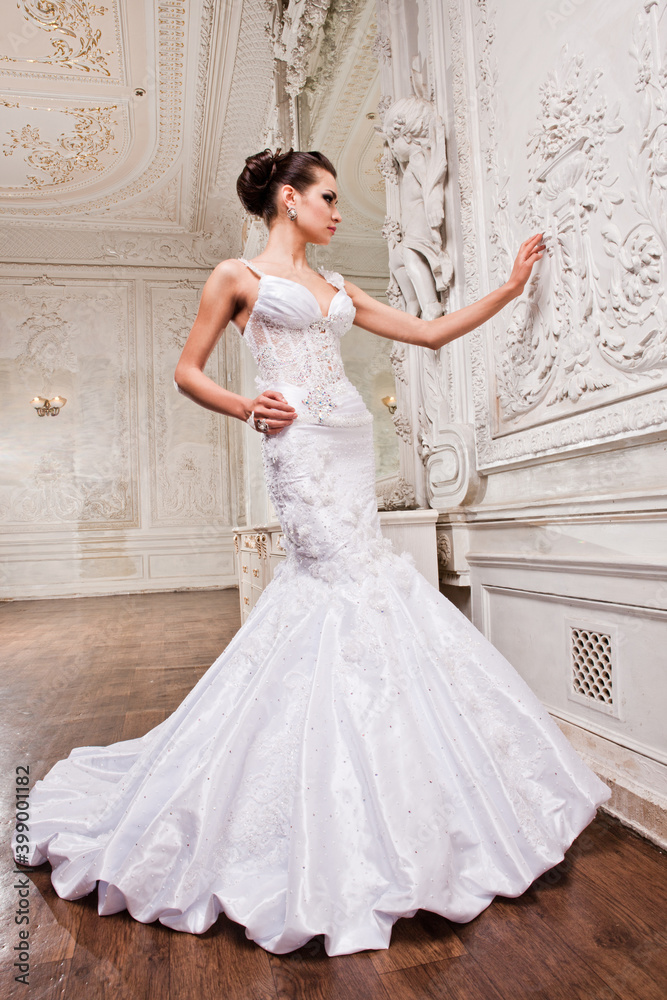 Fototapeta premium Beautiful bride in a white wedding dress in a light old classic interior