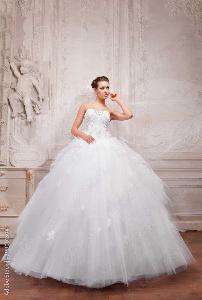 Beautiful bride in a white wedding dress in a light old classic interior