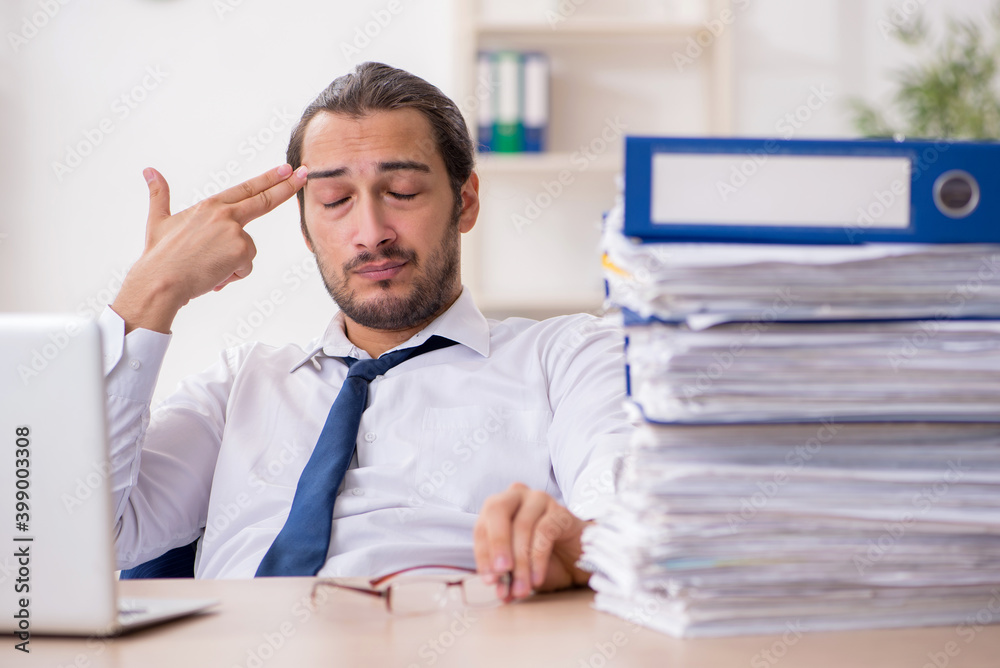 Young businessman unhappy with excessive work in the office Young businessman unhappy with excessive work in the office