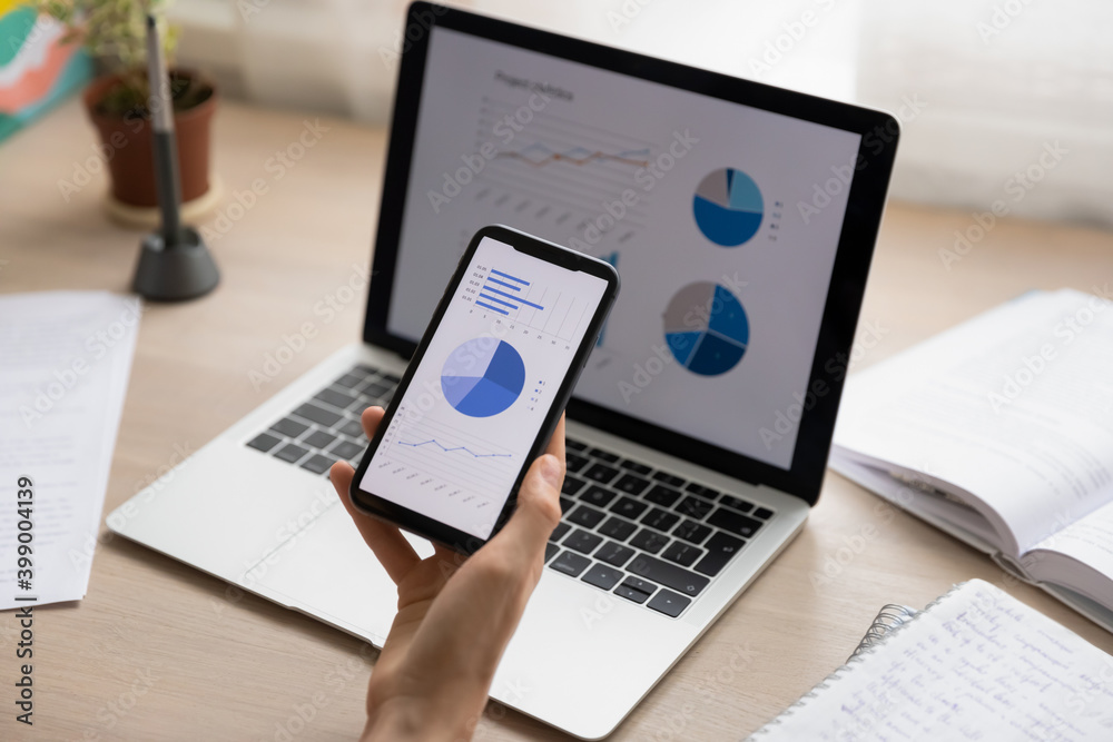 Close up businesswoman holding working with project statistics on devices, presentation with graphs and diagrams on laptop and phone screens, entrepreneur accountant analyzing financial data Close up businesswoman holding working with project statistics on devices, presentation with graphs and diagrams on laptop and phone screens, entrepreneur accountant analyzing financial data