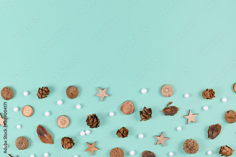 Seasonal decoration like wood slices and cones and Christmas star and snowball ornaments on mint green background with empty copy space Seasonal decoration like wood slices and cones and Christmas star and snowball ornaments on mint green background with empty copy space