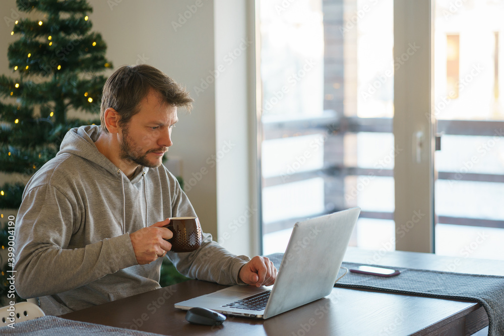 Young man works remotely from home while sitting at a table. Young man works remotely from home while sitting at a table.