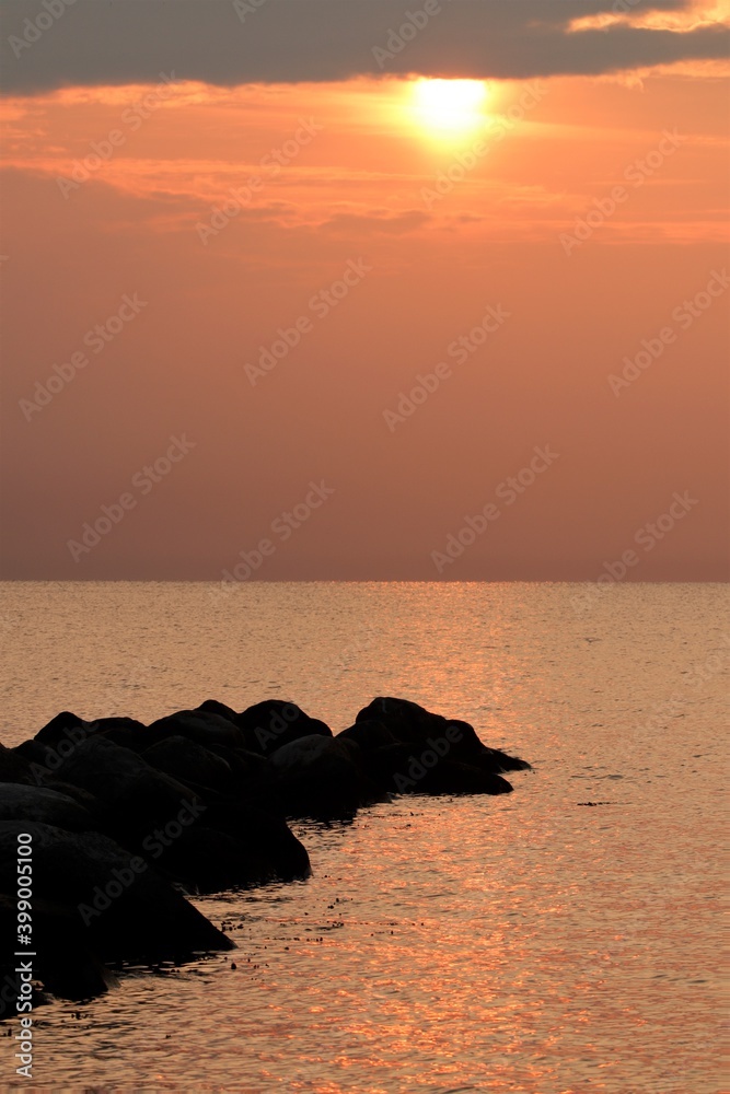 tranquil seascape with rock silhouettes and sun as vertical photos concept
