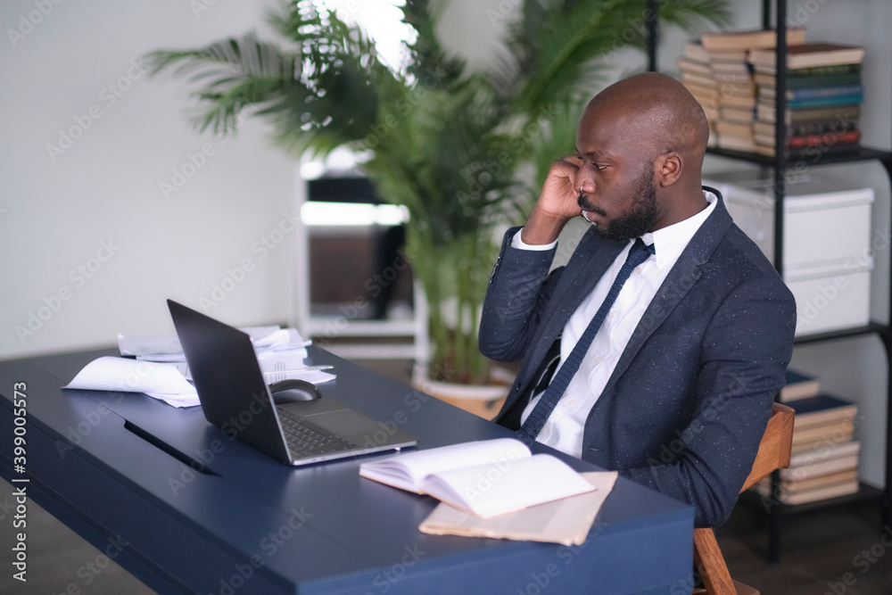 Serious African American Conducts Difficult Phone Negotiations. Head shot pensive young african american international company employee manager working with hard task at workplace. Serious African American Conducts Difficult Phone Negotiations. Head shot pensive young african american international company employee manager working with hard task at workplace.