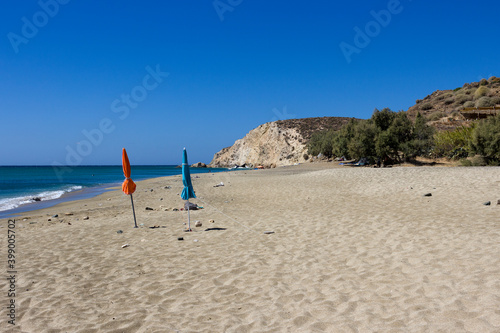 Anafi island, two closed umbrellas on the beautiful uncrowded Roukonas beach. Cyclades islands, Greece
