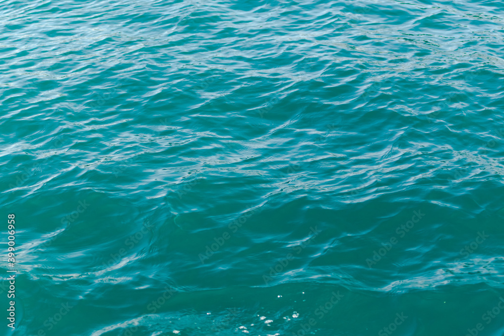 Small waves of azure sea with blurry background, used as a background or texture, soft focus