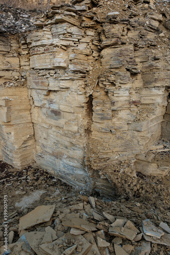 Ecke in einem Steinbruch: senkrechte Felswand mit Plattenkalk / Jurastein (Altmühltal) - vorne lose Steine
