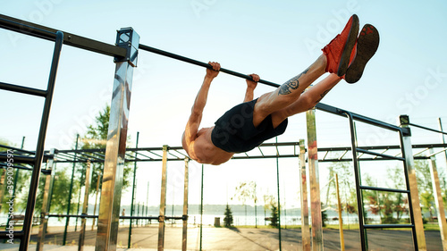 Strong athlete doing statics exercise on horizontal bar