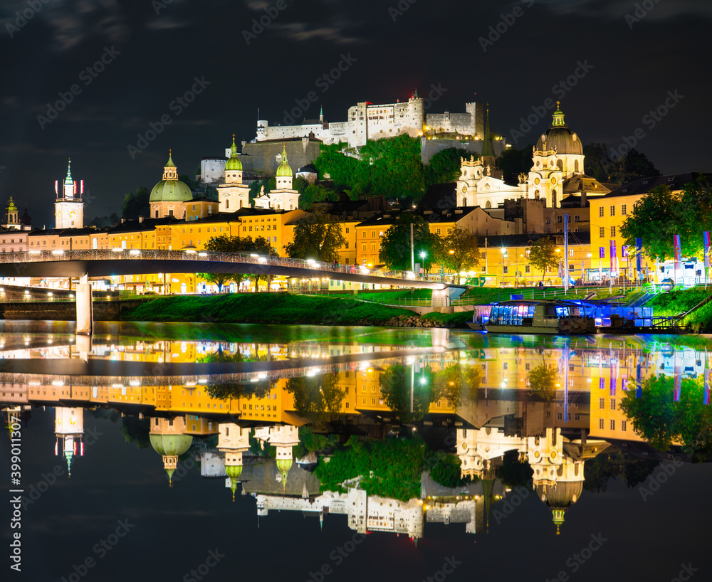 Salzburg at night. City skyline with Festung Hohensalzburg castle and reflection. Austria