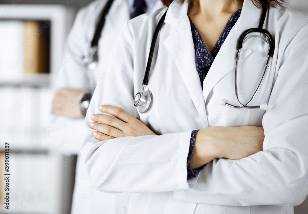 Group of modern doctors standing as a team with arms crossed in hospital office and ready to help patients. Medical help, insurance in health care, best disease treatment and medicine concept Group of modern doctors standing as a team with arms crossed in hospital office and ready to help patients. Medical help, insurance in health care, best disease treatment and medicine concept