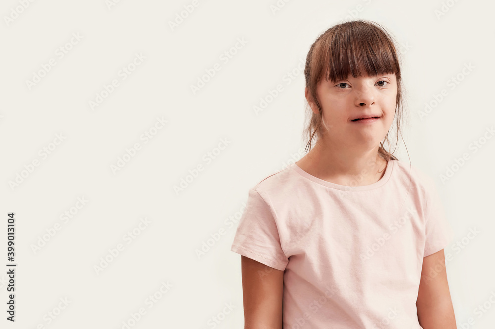 Portrait of disabled girl with Down syndrome looking at camera while posing isolated over white background Portrait of disabled girl with Down syndrome looking at camera while posing isolated over white background