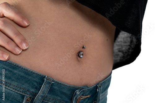 Belly button or navel piercing, of young woman wearing jeans isolated on white.