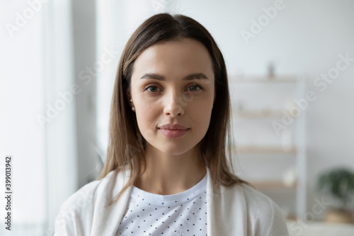 Head shot portrait serious beautiful young woman with perfect smooth skin looking at camera, standing at home, profile picture, focused attractive girl shooting video, recording vlog, job interview