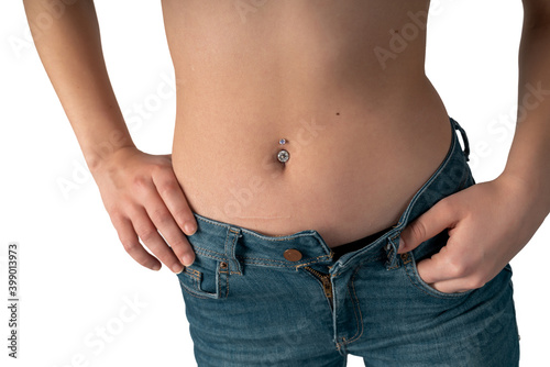 Belly button or navel piercing, of young woman wearing jeans isolated on white.
