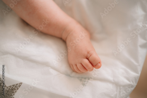 baby leg on a white sheet. skin care and nail cutting in newborns.