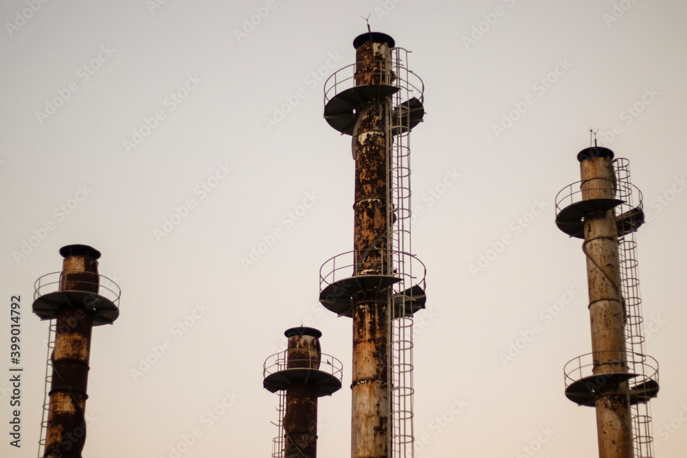 Naklejka premium Four industrial metal chimneys with sky in background