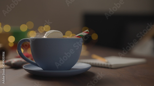 hot chocolate in blue cup in the evening with shopping list for holidays in notepad
