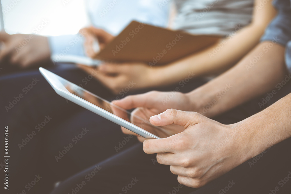 Group of casual dressed business people working at meeting or conference, close-up of hands. Businessman using tablet computer. Teamwork or coaching concept