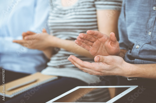 Business people clapping at meeting or conference, close-up of hands. Group of unknown businessmen and women in modern white office. Success teamwork, corporate coaching and applause concept