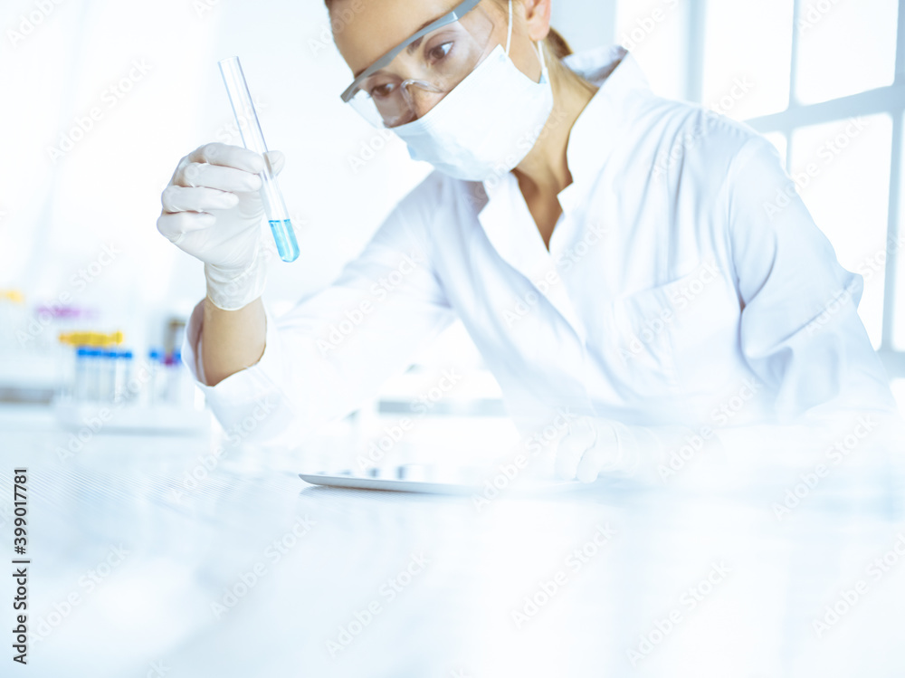 Female laboratory assistant analyzing test tube with blue liquid. Medicine, health care and researching concept Female laboratory assistant analyzing test tube with blue liquid. Medicine, health care and researching concept