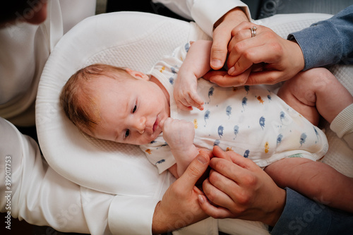 top view. Happy parents parents hold hands young son in a lounger for newborns.