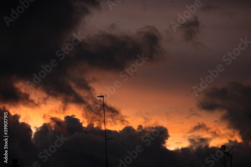 Atardecer anaranjado con nubes grises y pájaros volando (Madrid)