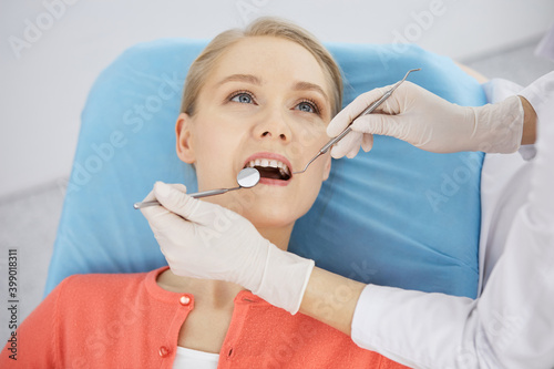 Smiling caucasian woman is being examined by dentist at dental clinic. Healthy teeth and medicine, stomatology concept