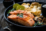 Roasted salmon steaks with fried cauliflower, fried brown champignons, lime and mayonnaise on wooden table
