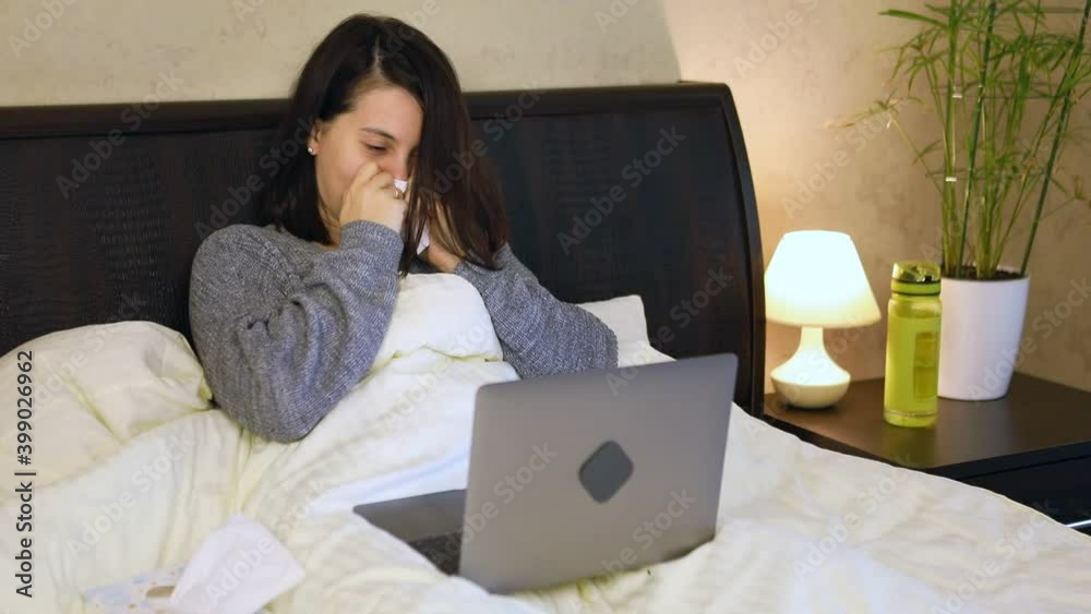 woman working on laptop laying in bed having flu woman working on laptop laying in bed having flu