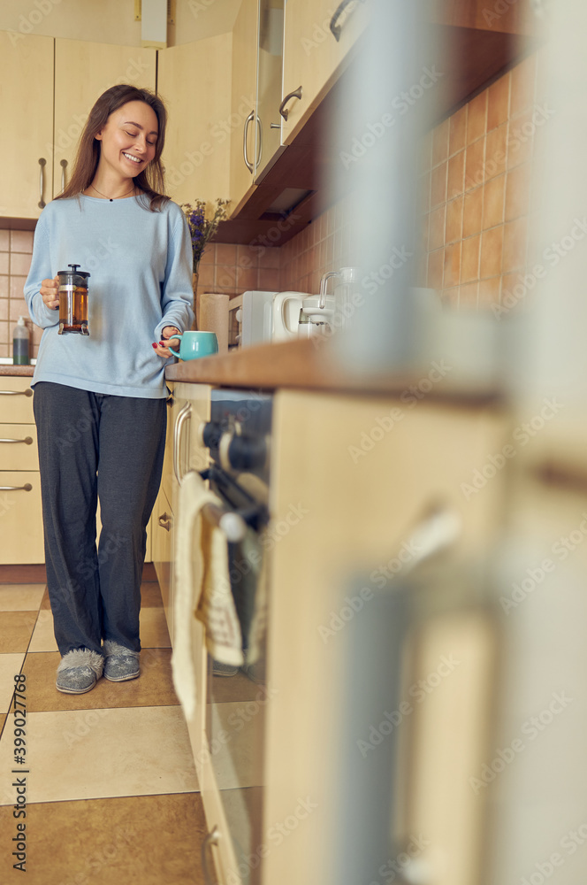 Young cheerful and happy woman is preparing tasty tea at her kitchen at home Young cheerful and happy woman is preparing tasty tea at her kitchen at home