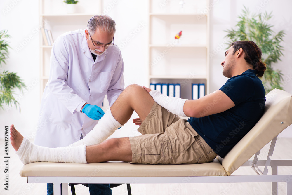 Fototapeta premium Young injured man visiting old doctor traumatologist