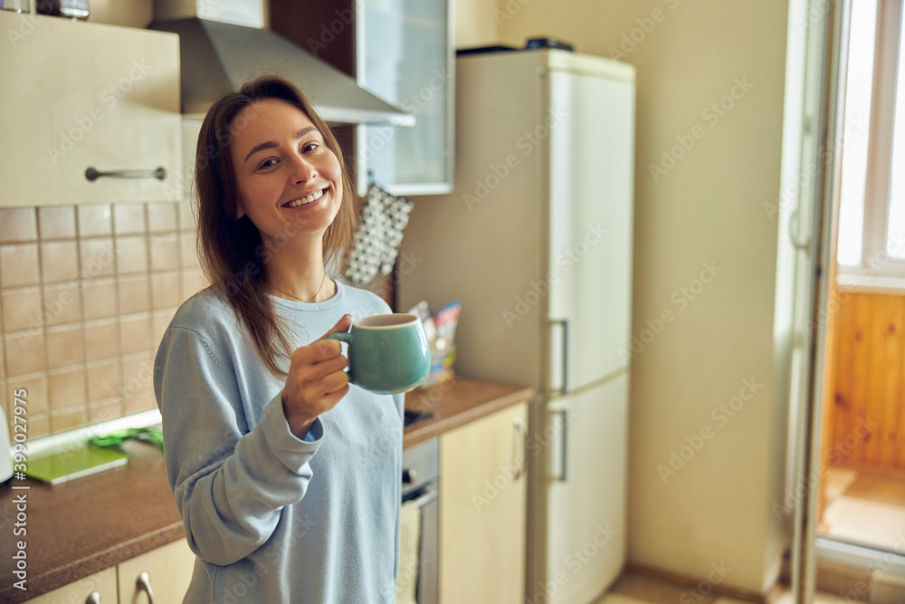 Young cheerful and happy woman is preparing tasty tea at her kitchen at home Young cheerful and happy woman is preparing tasty tea at her kitchen at home