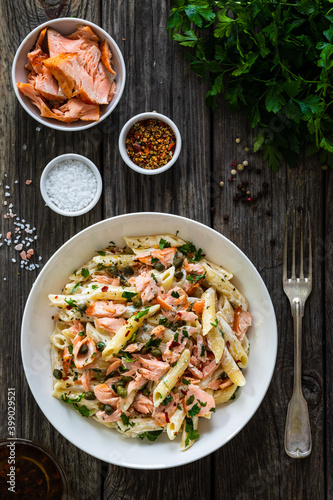 Penne with roasted salmon nuggets on wooden table
