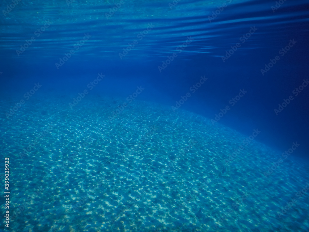 deep blue clear sea water with reflection on sandy bottom