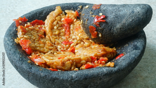 Penyet tempeh with chili sauce in a stone mortar. Focus selected